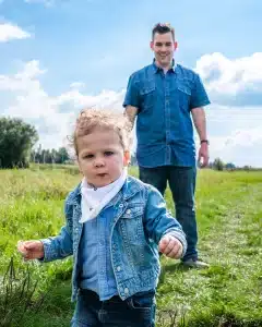 Vater und Kind springen beim Familienshooting auf einer Wiese